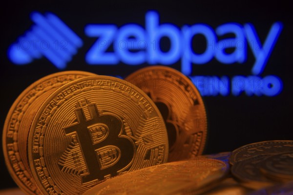 Dhaka, Bangladesh- 02 June 2025: Close-up of Bitcoin coins with the zebpay logo visible on a screen in the background