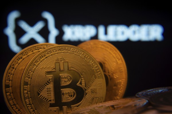Dhaka, Bangladesh- 03 Sep 2025: Close-up of Bitcoin coins with the XRP Ledger logo visible on a screen in the background