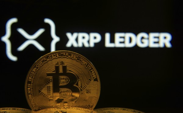 Dhaka, Bangladesh- 03 Sep 2025: Close-up of Bitcoin coins with the XRP Ledger logo visible on a screen in the background