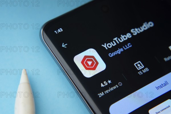 Dhaka, Bangladesh- 29 May 2025: On a blue surface, a smartphone displays the youtube studio app within the Google Play Store