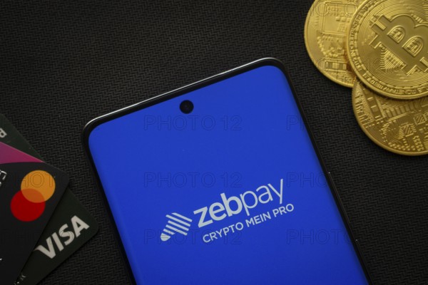 Dhaka, Bangladesh- 15 June 2025: Smartphone displaying zebpay logo surrounded by Bitcoin coins and payment cards