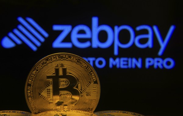 Dhaka, Bangladesh- 04 April 2025: Close-up of Bitcoin coins with the ZebPay logo visible on a screen in the background