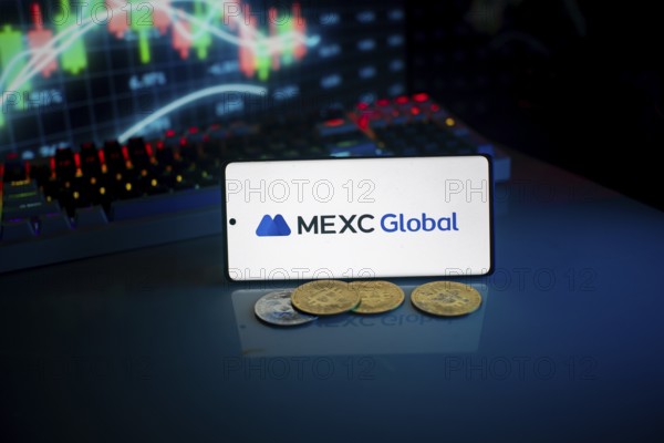 Phone shows MEXC Global logo with crypto coins and trading screen illuminated