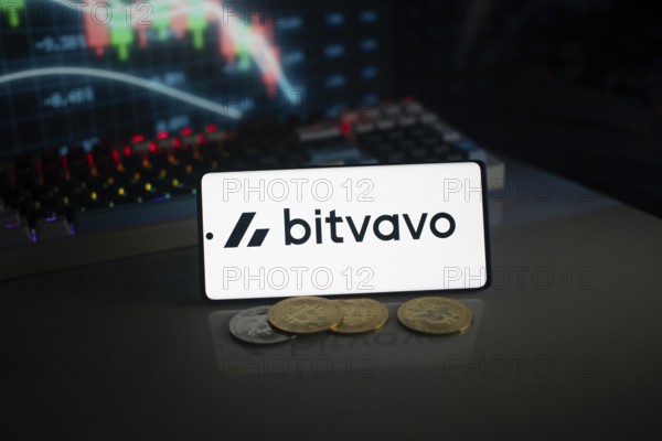 Bitvavo logo on smartphone with coins, neon lights, and trading charts in background