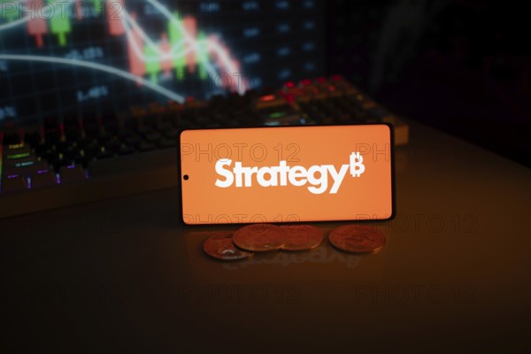 Phone shows Strategy logo with Bitcoin symbol and crypto coins on vivid screen
