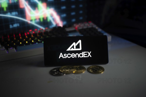 AscendEX logo with cryptocurrency coins on a desk, trading graphs in background