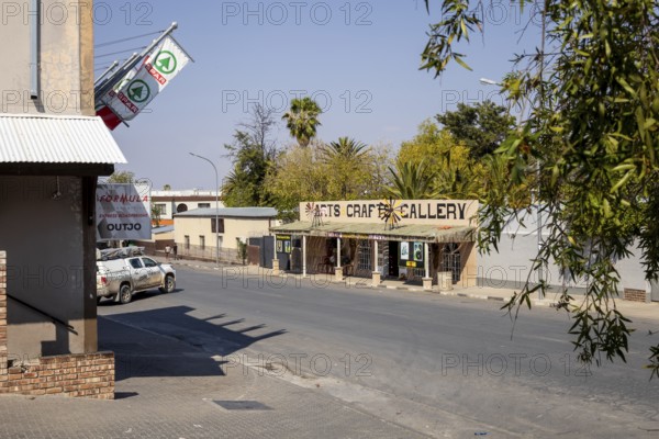 Street view of a modern building with a restaurant or café entrance in Outjo, Namibia 12 Augusto 2025: showing parked cars, outdoor seating, and clear blue sky