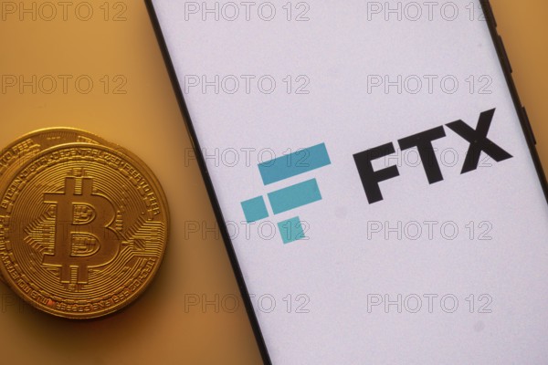 FTX logo displayed on a phone beside a Bitcoin on an orange background