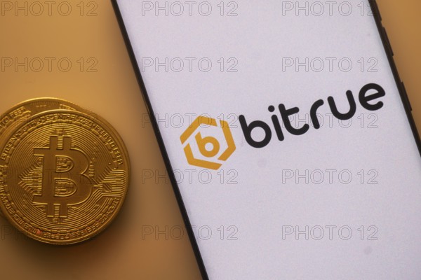 Smartphone with Bitrue logo next to a Bitcoin on an orange background