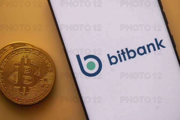 Smartphone featuring Bitbank logo alongside a Bitcoin on an orange background