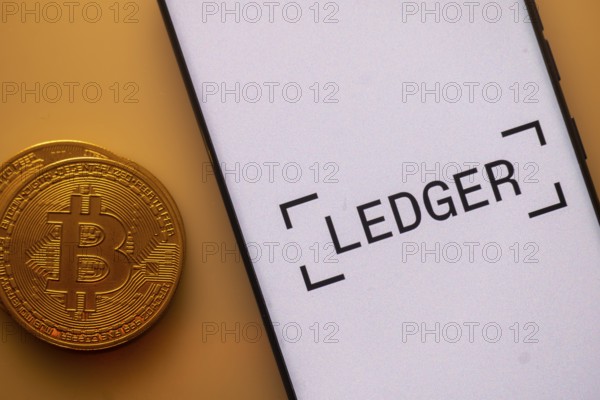 Bitcoin displayed next to a smartphone with Ledger app interface on white background