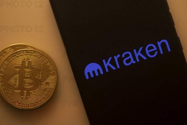 Bitcoin displayed with smartphone showing Kraken app interface on black background