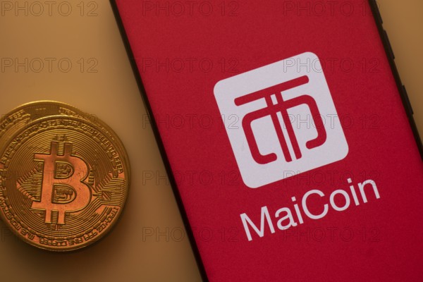 Bitcoin coin next to a smartphone featuring the MaiCoin logo on a red background