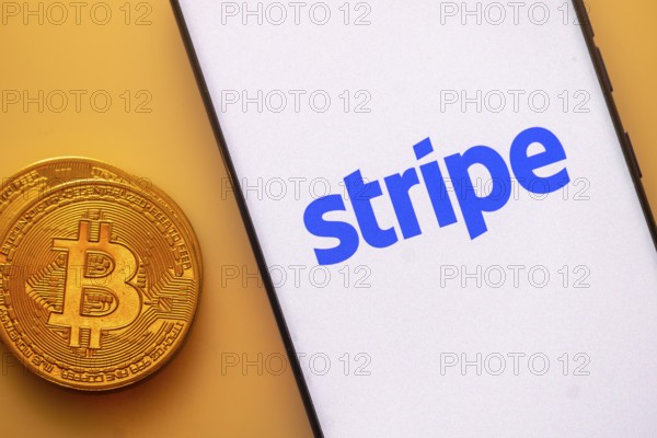 Bitcoin coin alongside a smartphone showing the Stripe logo on a light background