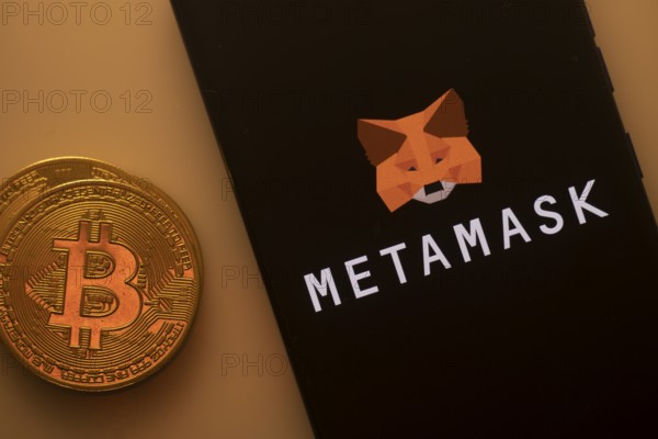Bitcoin coin near a smartphone with the MetaMask logo on a dark background
