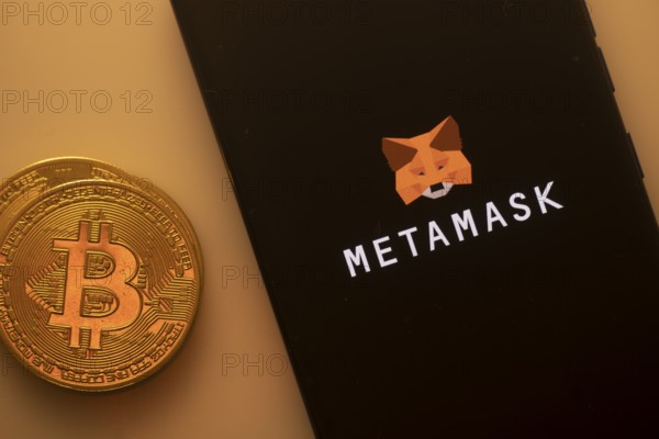 Bitcoin coin near a smartphone with the MetaMask logo on a dark background