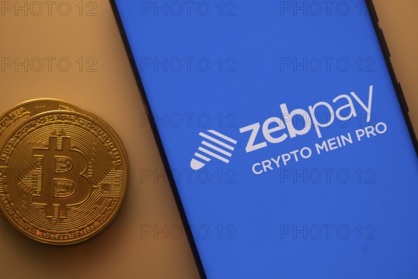 Bitcoin coin alongside a smartphone displaying the Zebpay logo on a blue screen
