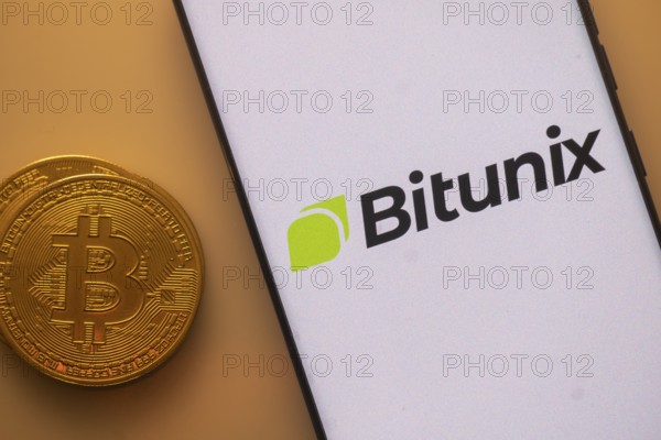 Bitunix app on phone screen next to a Bitcoin coin