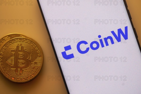 CoinW app shown on a smartphone next to a Bitcoin coin