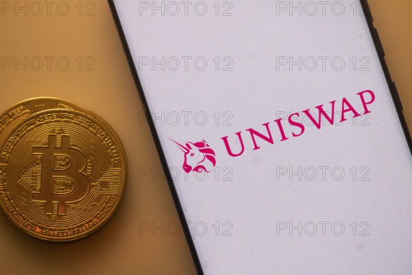 Uniswap app on a phone screen with a Bitcoin coin beside it
