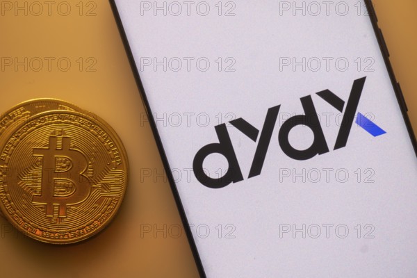 DYdX app displayed on a smartphone with Bitcoin coin on the side