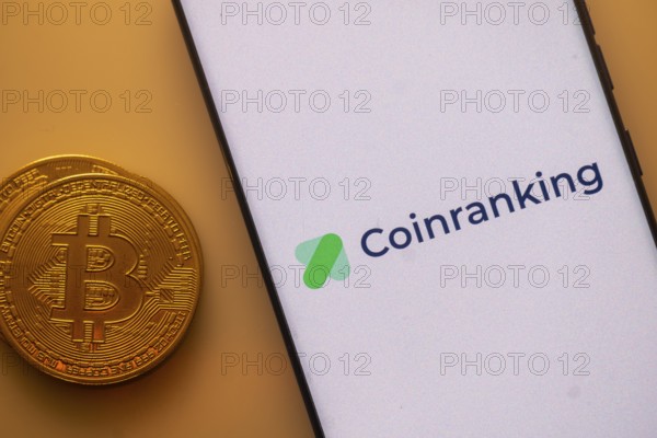 Coinranking app shown on phone screen with Bitcoin coin beside it