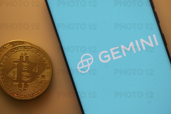 Gemini logo on a smartphone screen alongside a Bitcoin coin