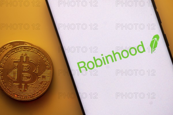 Robinhood logo displayed on a smartphone next to a Bitcoin coin