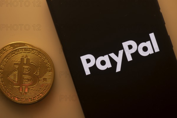 PayPal logo on smartphone screen next to Bitcoin, highlighting digital payments and financial transactions