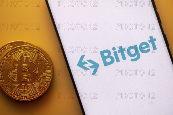 Bitget logo on a smartphone screen beside a Bitcoin coin on an orange background