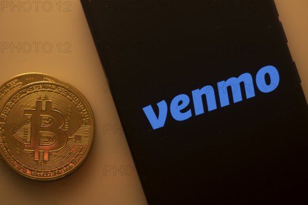 Venmo logo on smartphone screen beside Bitcoin, emphasizing digital transactions and payment services