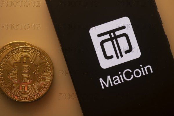 MaiCoin logo on smartphone next to Bitcoin, emphasizing cryptocurrency exchange and finance services