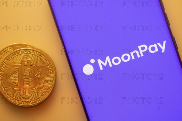 MoonPay logo on purple smartphone screen next to Bitcoin, focusing on digital payments and technology