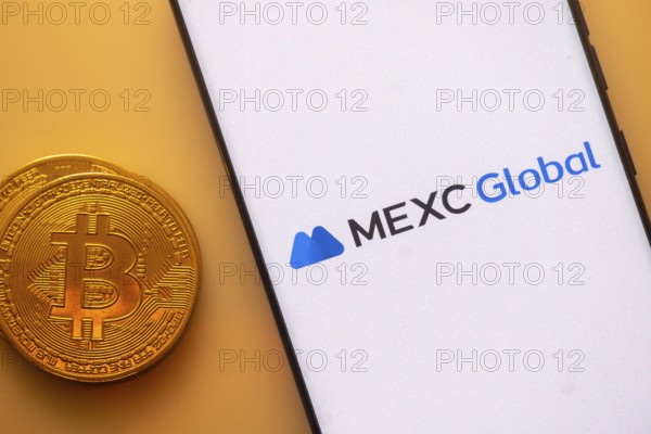 MEXC Global logo on smartphone screen beside a Bitcoin, emphasizing cryptocurrency and technology