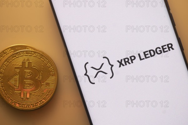 XRP Ledger logo on smartphone next to Bitcoin, emphasizing blockchain and cryptocurrency exchange
