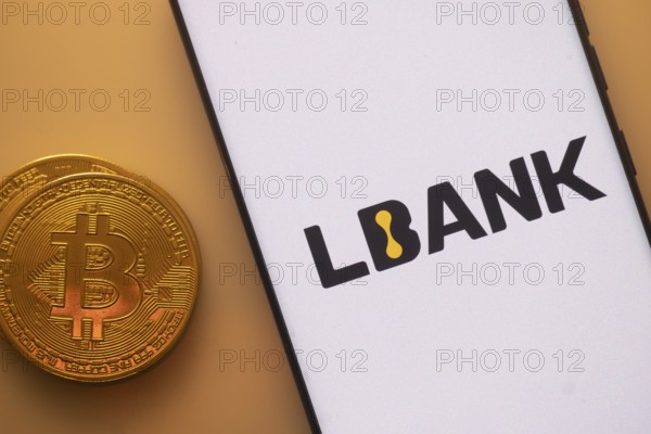 Bitcoin coin next to a phone with LBank logo on white screen