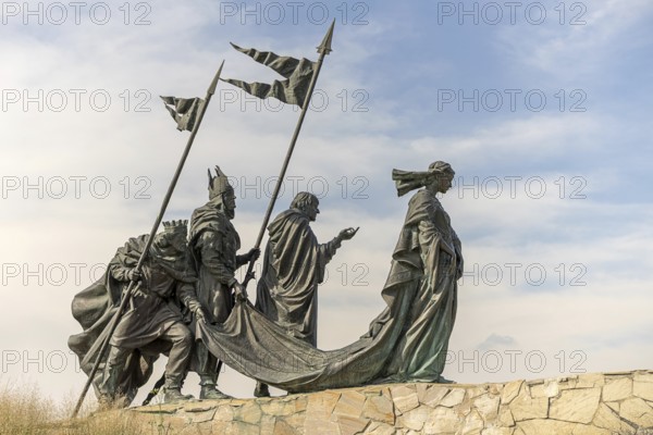 Sculpture group of historical figures with flags on a stone platform under a blue sky, Nibelungendenkmal Minoritenplatz Tulln Lower Austria Austria