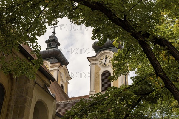 Baroque church towers with clocks, surrounded by deciduous trees under a cloudy sky, parish church St.Stephan Tulln Lower Austria Austria