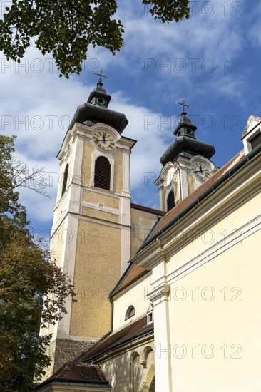 Baroque church towers with clocks rise against a clear blue sky in the afternoon light, St.Stephan parish church Tulln Lower Austria Austria