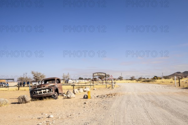 Solitaire's car graveyard in Namibia features rusted vintage cars near small desert buildings, set against dunes and mountains, capturing desert charm and isolation