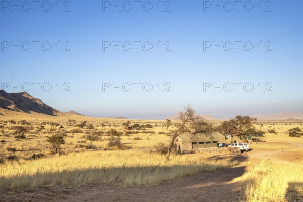 The vast Namib Desert from Spreetshoogte Pass, with hazy plains, rugged mountains, and a lone house on the ridge under the bright sky