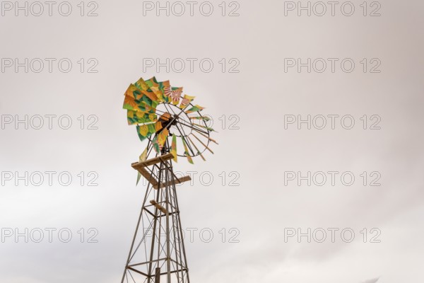 A solitary water pump stands in the arid landscape near Solitaire, Namibia, under a dramatic, cloudy sky