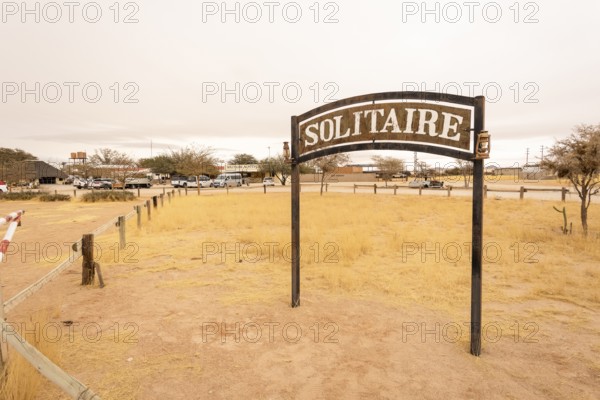 The remote desert settlement of Solitaire in Namibia - 27 August, 2025: features a sign displaying the town's name, set against golden sand dunes and rugged mountains