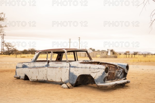 Solitaire's car graveyard in Namibia features rusted vintage cars near small desert buildings, set against dunes and mountains, capturing desert charm and isolation
