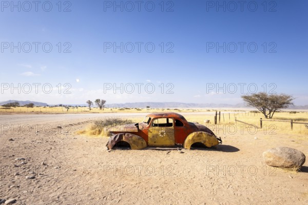 Solitaire's car graveyard in Namibia features rusted vintage cars near small desert buildings, set against dunes and mountains, capturing desert charm and isolation