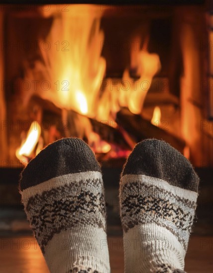 Feet in christmas socks warming by cozy fireplace on winter evening, AI generated