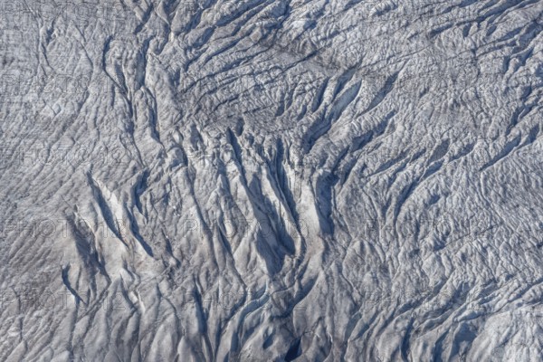 Crevasses and streaks mark the surface of the glacier. The sunlight highlights these unique geological formations. Overview of climate change in action. Gorner Glacier, Zermatt, Valais, Alps, Swiss