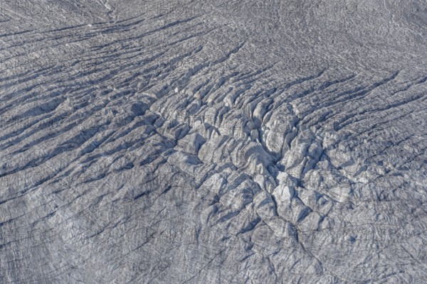 Crevasses and streaks mark the surface of the glacier. The sunlight highlights these unique geological formations. Overview of climate change in action. Gorner Glacier, Zermatt, Valais, Alps, Swiss