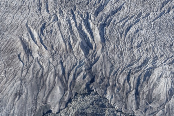 Crevasses and streaks mark the surface of the glacier. The sunlight highlights these unique geological formations. Overview of climate change in action. Gorner Glacier, Zermatt, Valais, Alps, Swiss