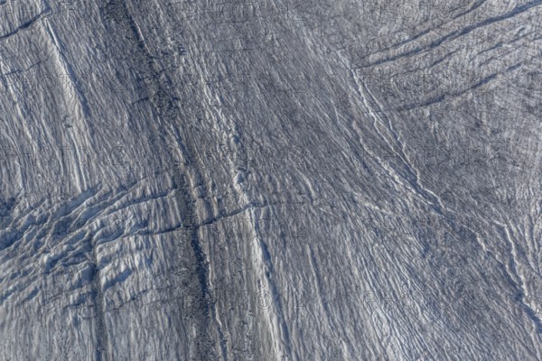 Crevasses and streaks mark the surface of the glacier. The sunlight highlights these unique geological formations. Overview of climate change in action. Gorner Glacier, Zermatt, Valais, Alps, Swiss